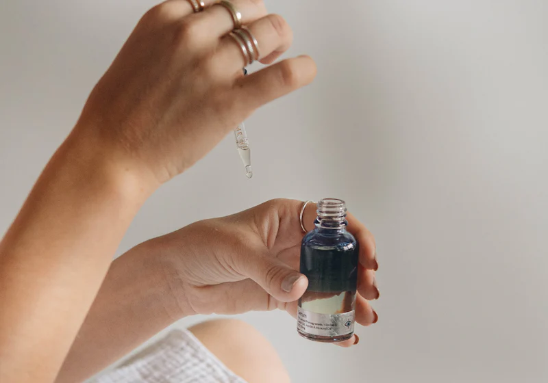 Tangan memegang botol penitis kosmetik